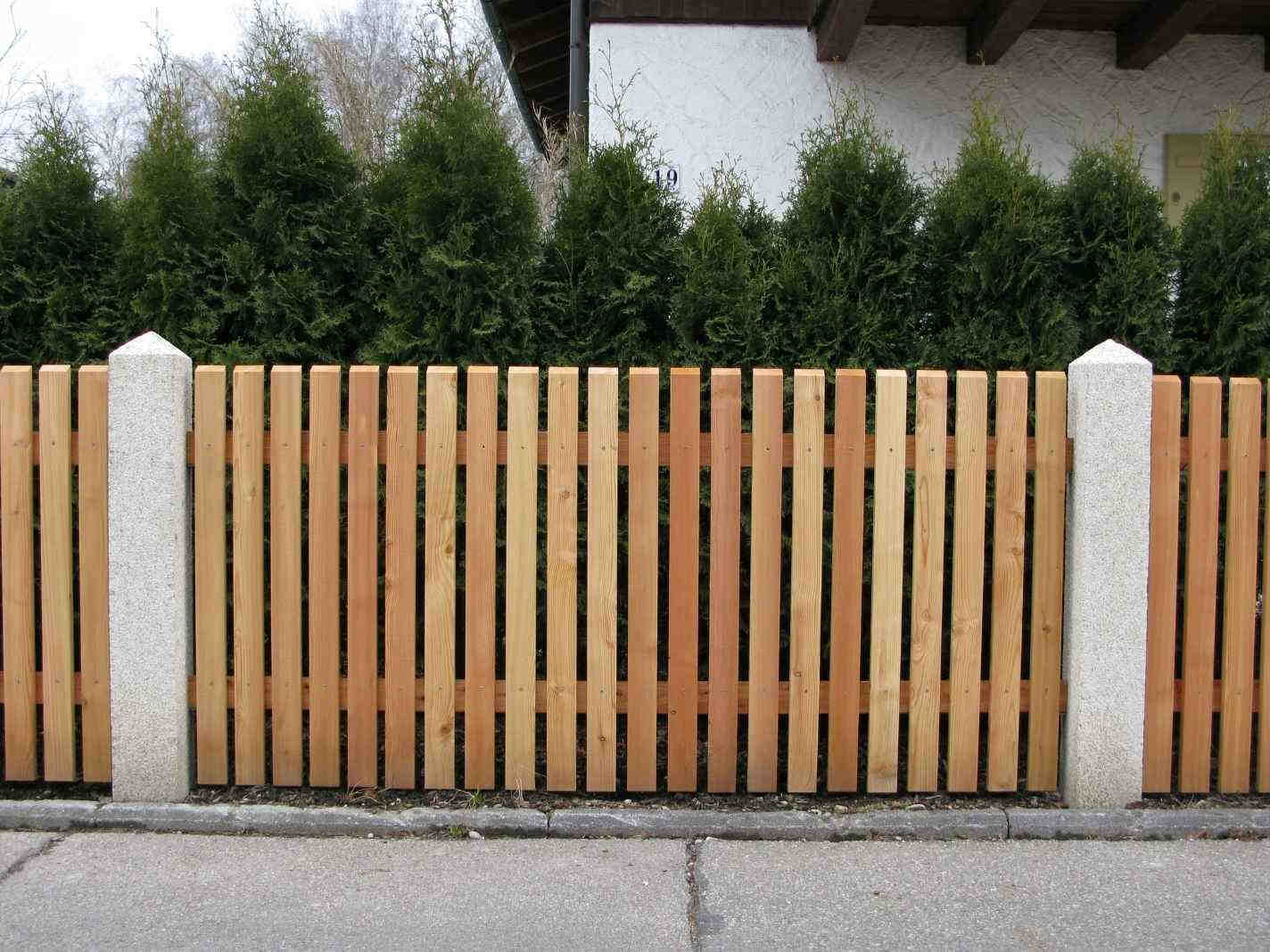 Klassischer Hobellattenzaun aus Holz mit gleichmäßig angeordneten Latten für eine gepflegte und natürliche Gartenoptik